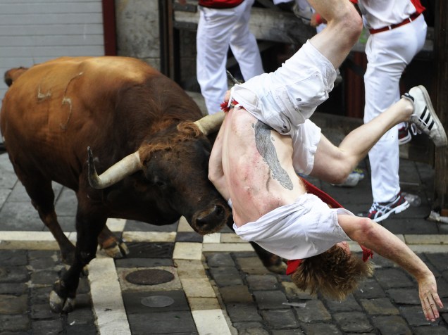 Foliões tentam se esquivar dos touros durante o "encierro", a famosa corrida de touros do Festival de São Firmino, em Pamplona, Espanha