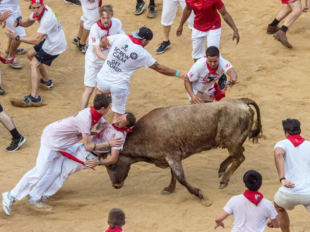 Foliões tentam se esquivar dos touros durante o "encierro", a famosa corrida de touros do Festival de São Firmino, em Pamplona, Espanha
