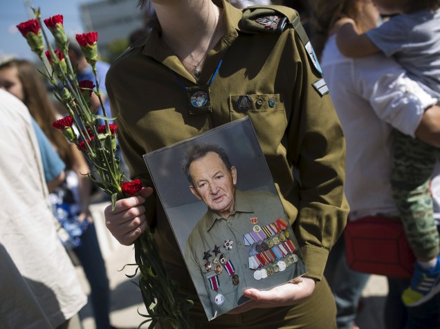 Soldado israelense segura foto de um veterano da Segunda Guerra Mundial durante parada em preparação para o Dia da Vitória, aniversário da vitória dos Aliados sobre a Alemanha Nazista