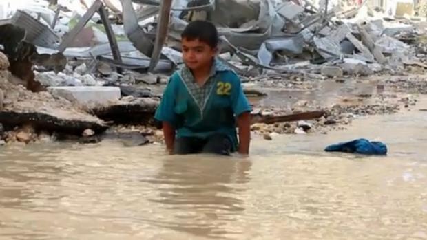 Criança brinca em cratera cheia de água que virou piscina improvisada em Alepo, na Síria