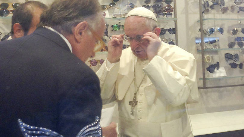 O papa Francisco experimenta óculos em uma ótica de Roma