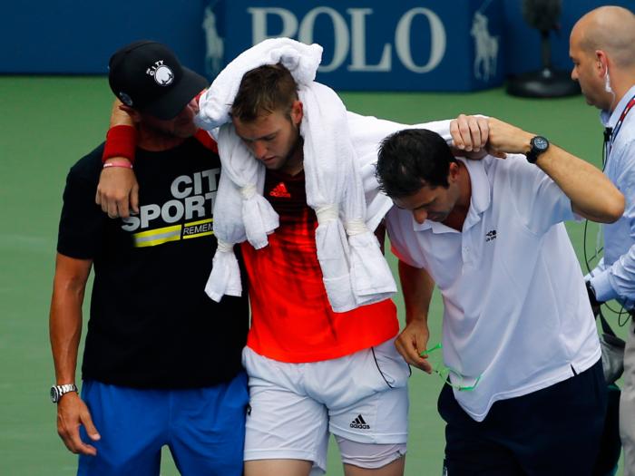 Jack Sock deixa a quadra Grandstand carregado pelos médicos do US Open