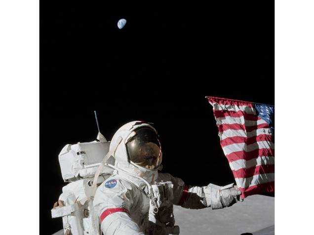 <p>O comandante da Apollo 17 Eugene A. Cernan segura uma bandeira americana em foto tirada em 1972</p>