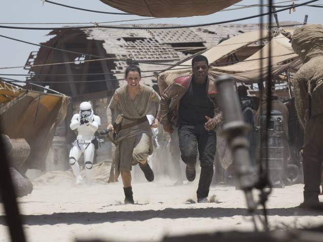 Rey (Daisy Ridley) e Finn (John Boyega) fogem das tropas do Império no deserto de Jakku em cena do filme Star Wars: Episódio VII - O Despertar da Força