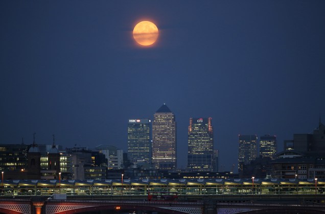 Lua cheia surge sobre Canary Wharf em Londres, Inglaterra