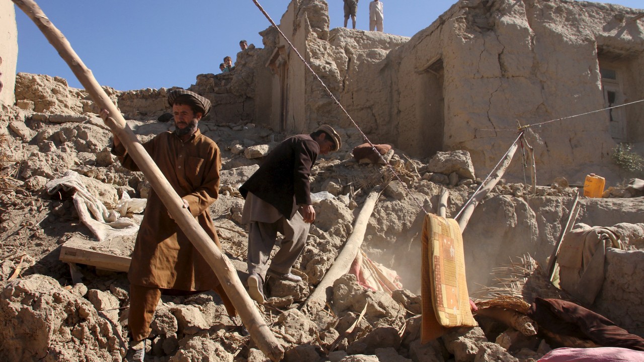 Homens recolhem seus pertences em meio aos destroços após terremoto que atingiu o norte do Afeganistão - 27/10/2015