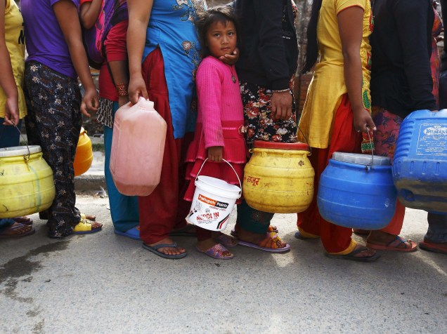 Pessoas aguardam na fila para pegar água próximo a abrigos improvisados para ajudar as vítimas do terremoto que atingiu Katmandu no sábado (25)
