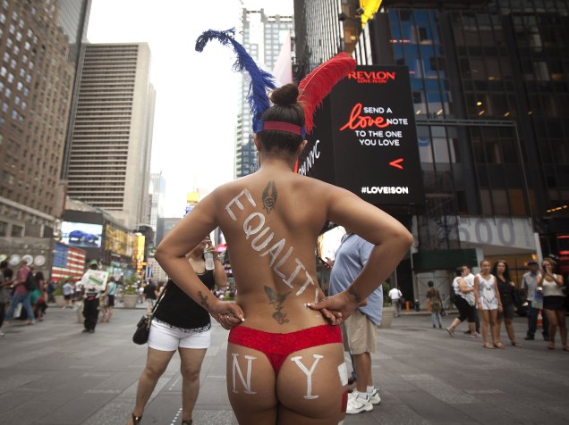 Mulheres fazendo topless posam com turistas em troca de gorjetas na Times Square, Nova York