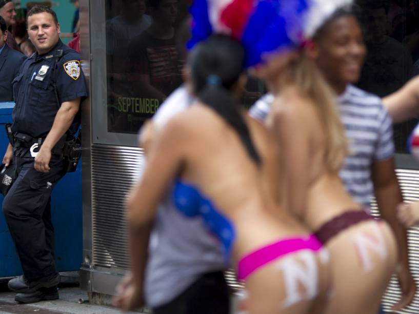 Mulheres fazendo topless posam com turistas em troca de gorjetas na Times Square, Nova York
