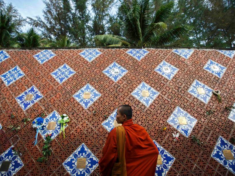 Na Tailândia, monge ao lado de memorial em forma de onda