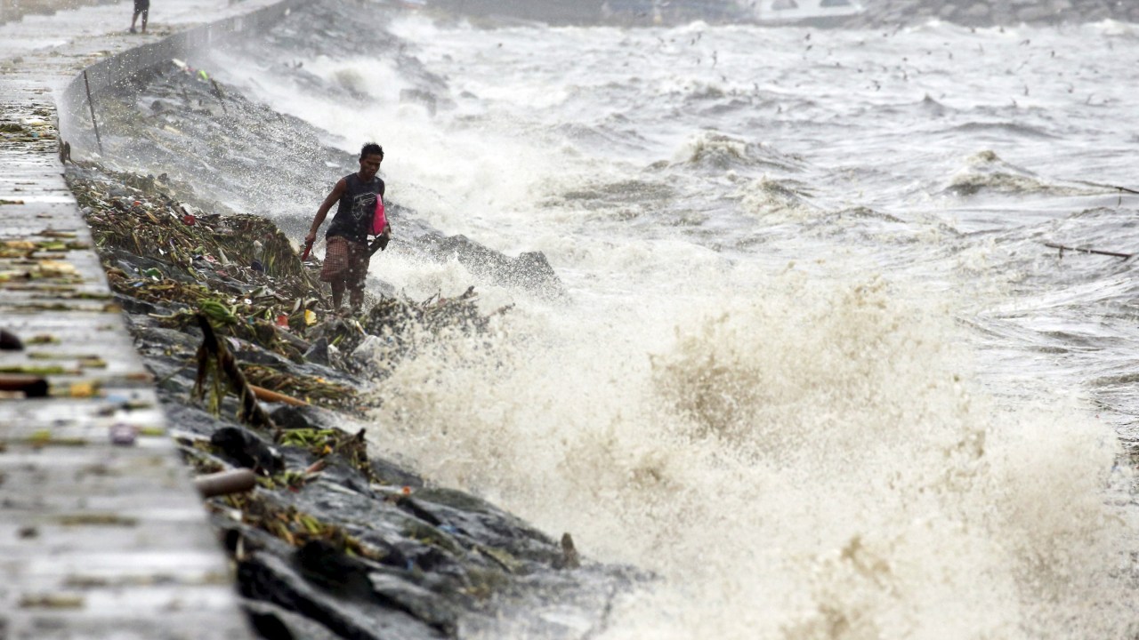 Residentes procuram por pertences entre ondas causadas pelo tufão Koppu, em Manila