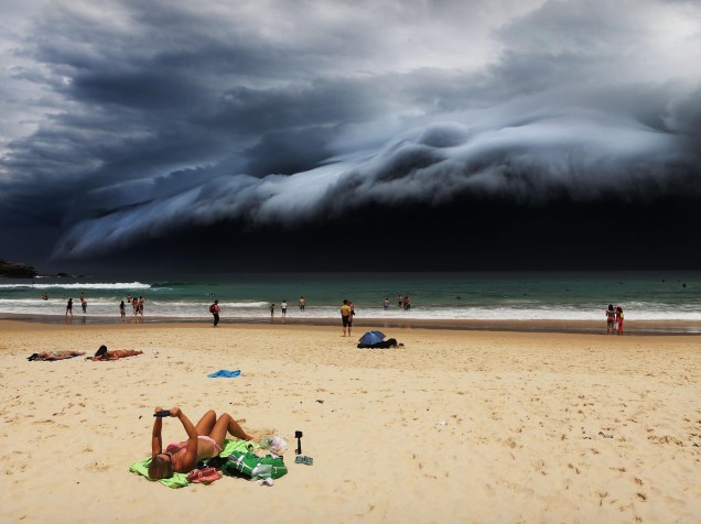 Nuvem de tsunami, é vista sobre o céu de Sydney, na Austrália, enquanto uma banhista lê um livro. Foto vencedora na categoria Natureza