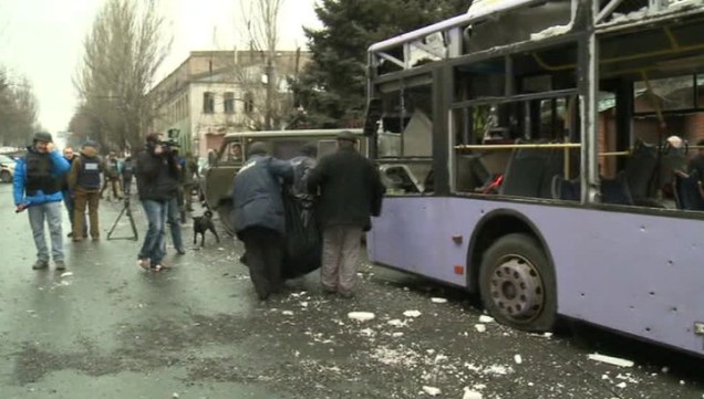 Pessoas carregam uma vítima de um projétil que atingiu um trólebus, em Donetsk