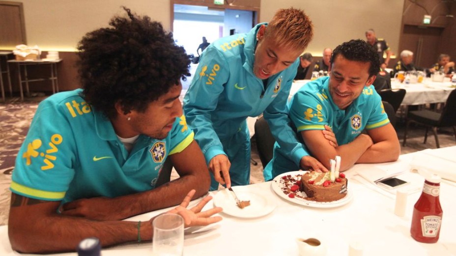 Neymar distribui fatias de seu bolo de aniversário aos colegas Dante e Fred, na concentração da seleção brasileira