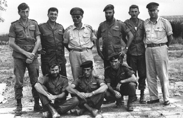Sharon (segundo de pé da esquerda para direita) em 1955. Ao seu lado está Moshe Dayan, então chefe do estado-maior