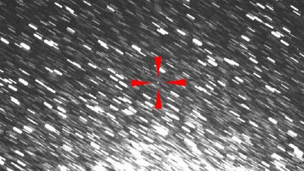 O asteroide 2012 DA14 é o pequeno ponto ao centro, indicado pelas marcas em vermelho. As manchas brancas são imagens de estrelas, borradas porque o telescópio acompanhava a movimentação do asteroide.