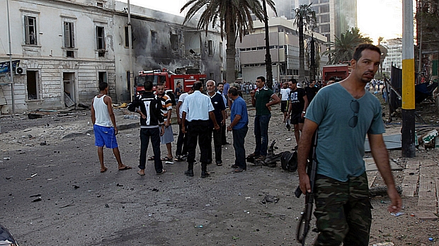 Curiosos observam como ficou prédio do governo Líbio atingido por explosão nesta terça
