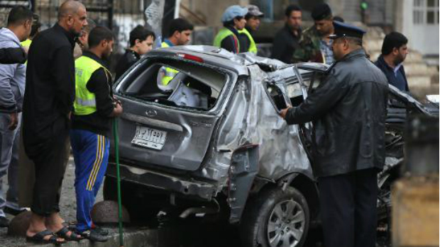 Iraquianos observam o local de um ataque com um carro-bomba no bairro de Karrada, na zona central de Bagdá