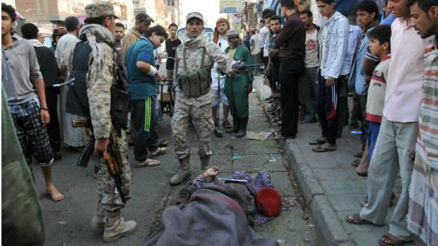 Soldados iemenitas e vizinhos observam o corpo inerte do comandante Mohamed Guawza depois de ser baleado em Sanaa, em 5 de maio de 2014