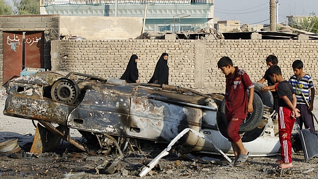 Moradores observam destroços de carro-bomba em Mahmudiya, a 30 quilômetros de Bagdá