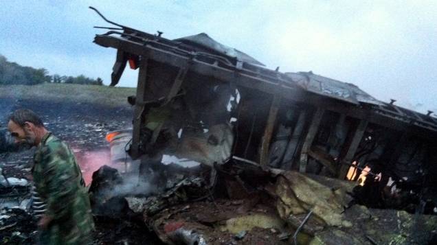 Homem é fotografado ao lado dos destroços do Boing 777 da Malasya Airlines, abatido na região de Donastek, na Ucrânia oriental. A aeronave saiu de Amsterdão rumo a Kuala Lumpur e transportava 298 passageiros