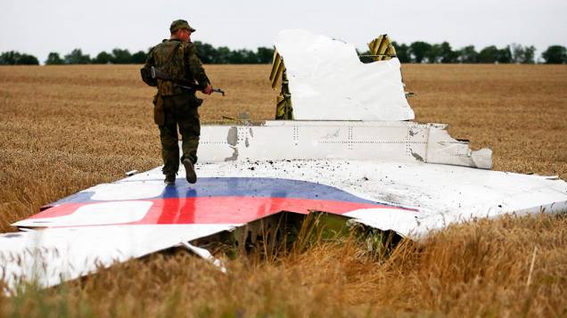 Separatista pró-Moscou anda sobre um destroço do Boeing 777 da Malaysia Airlines que caiu na região de Donetsk, na Ucrânia oriental