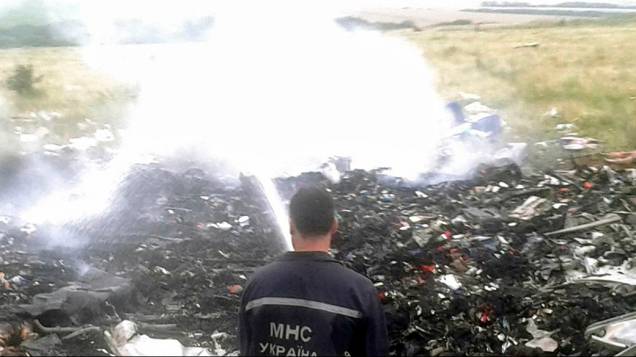 Oficiais do Ministério de Emergências trabalham no local onde o Boing 777 da Malaysia Airlines caiu na região de Donetsk, na Ucrânia oriental. Segundo as autoridades, o avião foi abatido sobre o território por militantes pró-Rússia, matando as 298 <br>pessoas que estavam a bordo