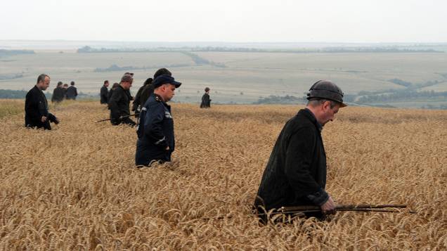 Um grupo de mineiros ucranianos ajuda equipes de resgate na busca dos corpos das vítimas em um campo de trigo no local da queda de um avião transportando 298 pessoas que seguia de Amsterdã para Kuala Lumpur, em Grabovka, na Ucrânia