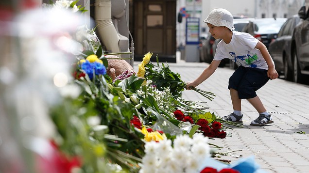Menino coloca flores em frente à embaixada holandesa em Moscou em homenagem às vítimas do voo da Malaysia Airlines, que caiu na Ucrânia