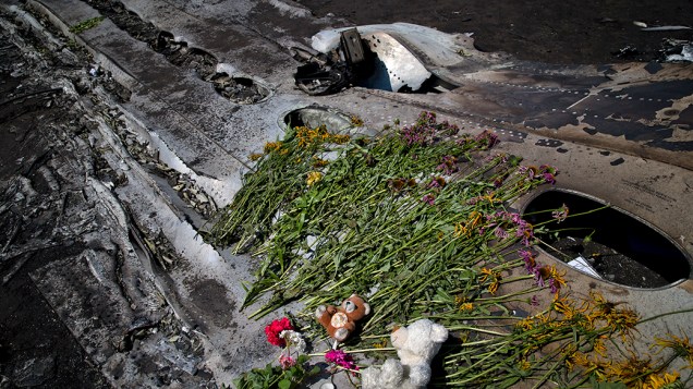 Brinquedos e flores são colocadas sobre a fuselagem carbonizada no local do acidente do Boing 777 da Malaysia Airlines, perto da aldeia de Hrabove, ao leste da Ucrânia. O abatimento da aeronave na última quinta-feira (17) matou as 298 pessoas que estavam a bordo