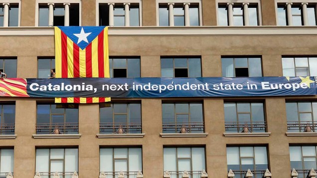 Membros da plataforma pró-independência catalã penduram bandeira gigante na Plaza de Catalunya em Barcelona