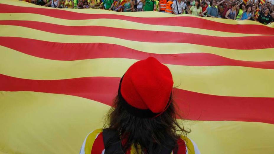 Os manifestantes nacionalistas catalães com bandeiras durante Dia Nacional da Catalunha em Barcelona