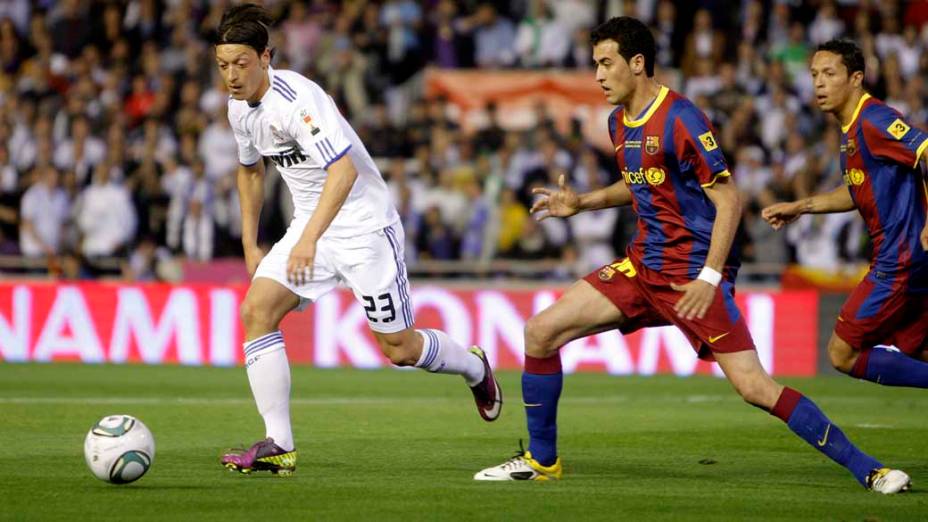 Ozil em lance com Sergio Busquets durante a partida entre Real Madrid e Barcelona pela final da Copa do Rei, Valência