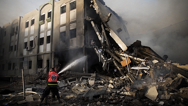 Bombeiros tentam extinguir fogo no prédio do Ministério do Interior palestino em Gaza, atingido por foguetes israelenses