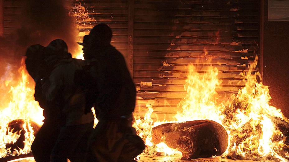 São Paulo - Vândalos se aproveitam da movimentação durante protestos contra o aumento das tarifas do transporte público, para saquear e atear fogo na porta de uma loja no centro de São Paulo