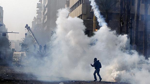Manifestante foge de lançamento de bomba de gás pela polícia em protesto no Cairo