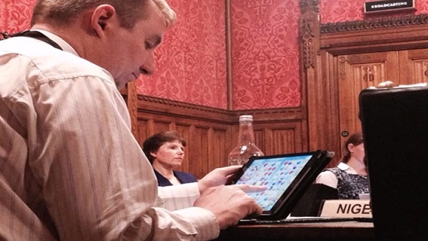 Nigel Mills joga Candy Crush em um iPad durante sessão de comitê