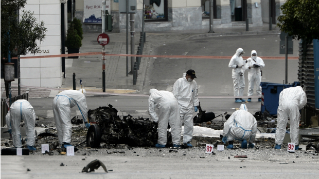 Técnicos da polícia grega inspecionam os destroços do carro-bomba que explodiu no centro de Atenas