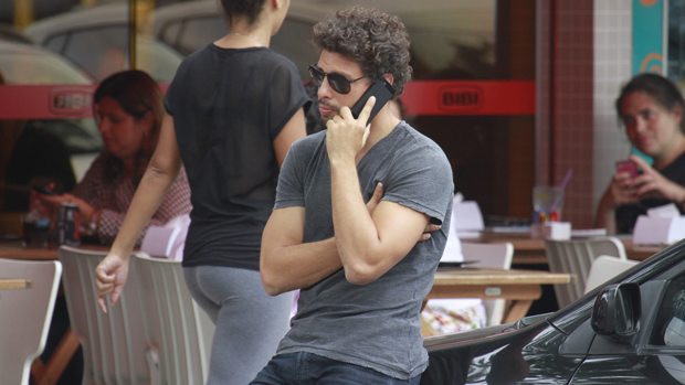 Cauã Reymond fala ao celular na Barra da Tijuca