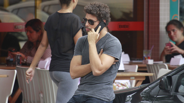 Cauã Reymond fala ao celular na Barra da Tijuca