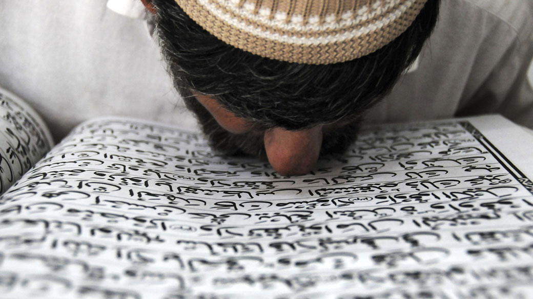Paquistanês beija o Corão, livro sagrado para os muçulmanos, durante o Ramadã em Peshawar, Paquistão