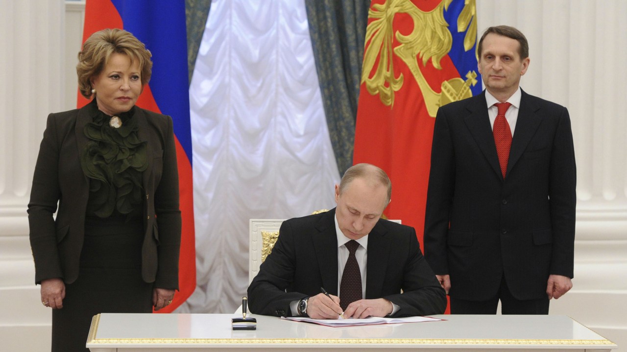 Cercado por líderes do Parlamento russo, o presidente Vladimir Putin promulgou as leis de anexação da península da Crimeia