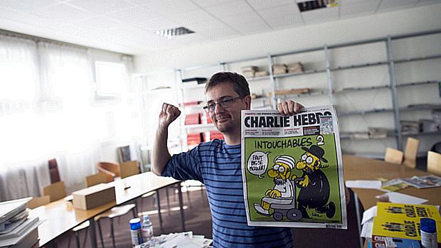 Charb, o cartunista reponsável pela publicação Charlie Hebdo, segura um exemplar da revista