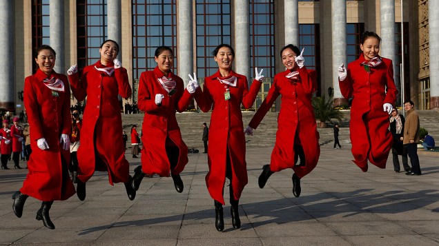Recepcionistas do Congresso Nacional do Partido Comunista Chinês tiram foto em frente ao edifício que recebe o evento