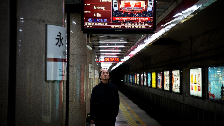 Em uma estação de metrô em Pequim, homem assiste à transmissão da cerimônia de abertura do 18º Congresso do Partido Comunista