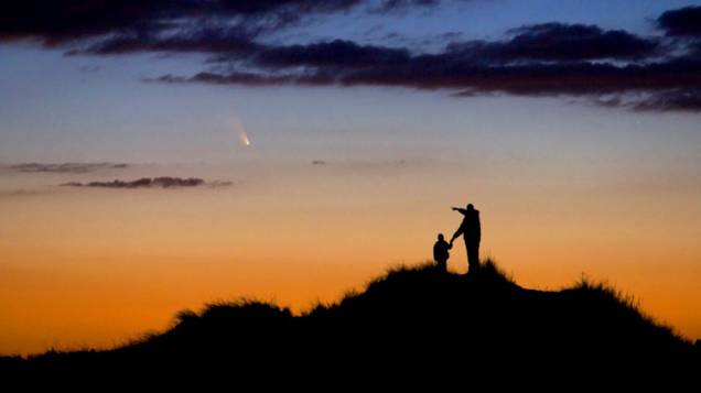 <p>Pai e filho observam a passagem do cometa Pan-STARRS na First Encounter Beach (Praia do Primeiro Encontro, em tradução livre), em Massachusetts, nos Estados Unidos</p>