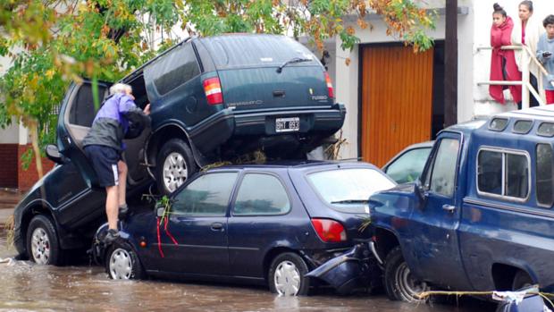 Homem sobe em carro em área inundada em La Plata, na Argentina
