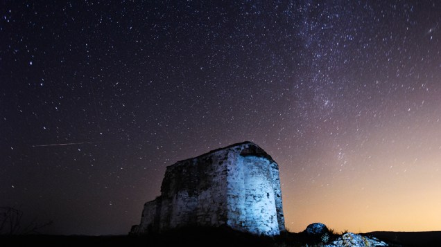 <p>A imagem em longa exposição mostra um meteoro Perseidas (esquerda) cruzando o céu sobre a igreja medieval de St. Ioan perto da aldeia de Potsurnentsi, late, na Bulgária</p>
