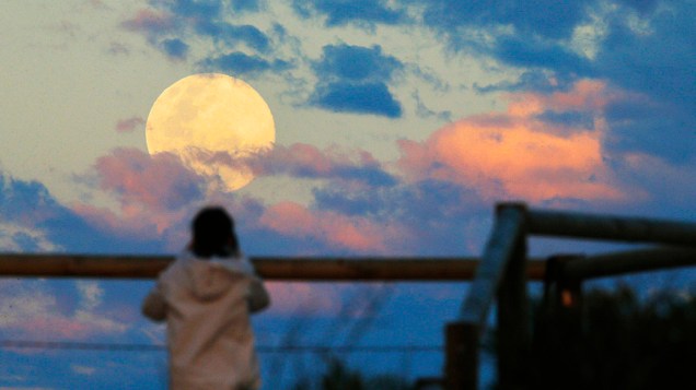 <p>Mulher assiste ao nascer da Lua em uma praia de Sydney, na Austrália</p>