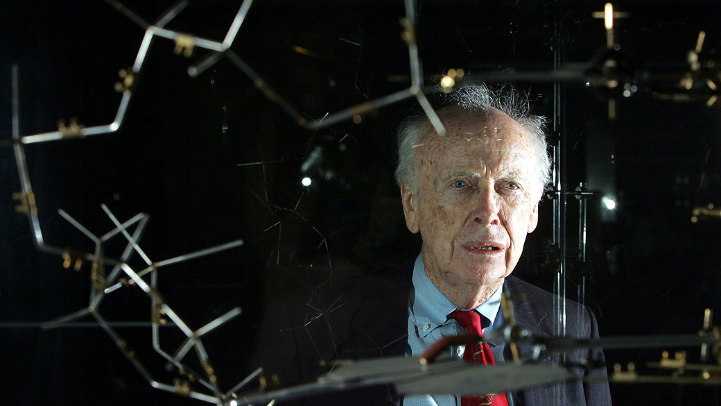 Cientista James Watson posa ao lado do modelo original elaborado por ele e por Francis Crick para explicar a estrutura do DNA
